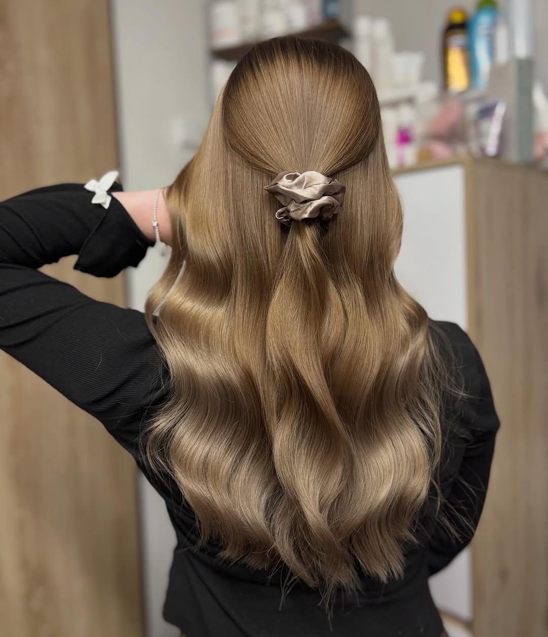 Žena s dlouhými upravenými vlnitými vlasy v kadeřnickém salonu